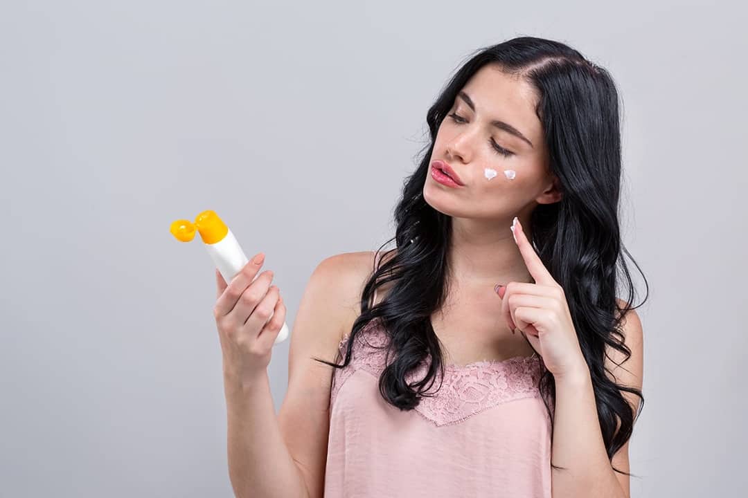 A young woman putting on sunscreen.